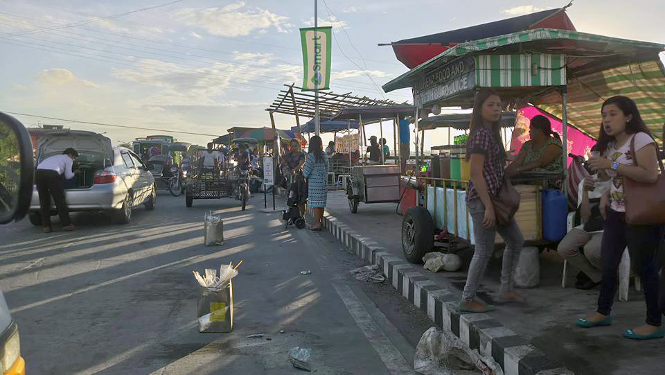 STALLS IN THE SIDEWALK - Food stalls along Ninoy Aquino Boulevard were inspected  by the City Health Office-EHSU headed by Dr. Ma. Carmela Go and Jose Leandro Ibarra. But while the stalls along the boulevard generate income to the city and stall owners, the “ingenious”  idea has worsened the traffic congestion in area and has made it unsafe for the pedestrians as the stalls occupied the sidewalk 24/7. If you want a night market, the stalls should be out (not just closed) during the day./Photo credits to Ms. Beng Nicdao.